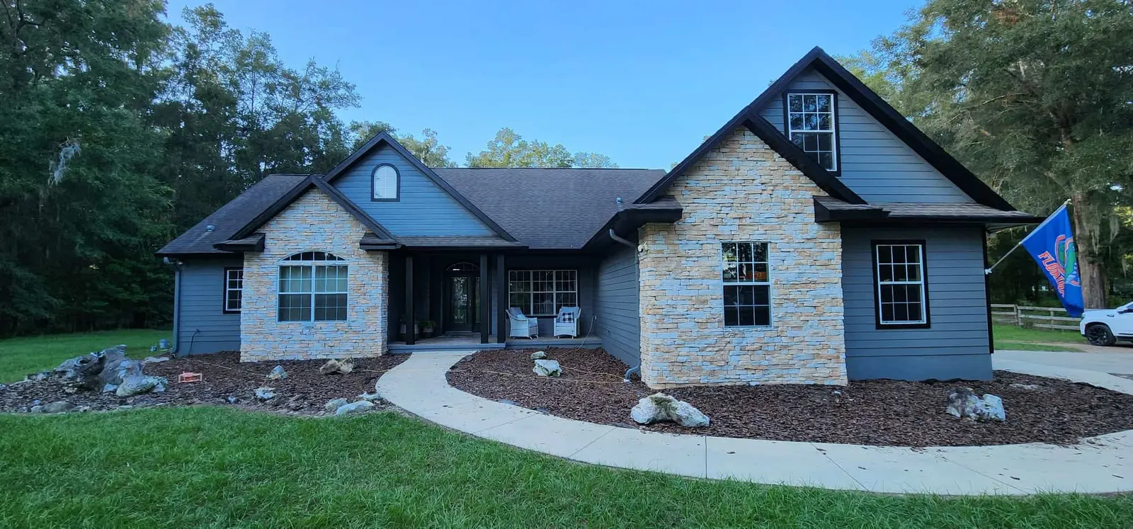 Single-story home with stone accents, slate blue siding and white trim