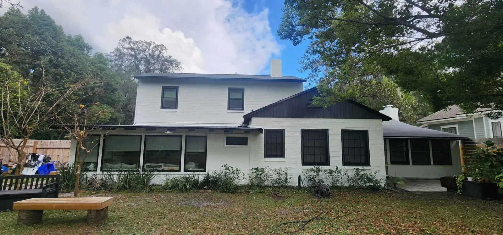 Two-story white home with black window frames and a dark metal roof section