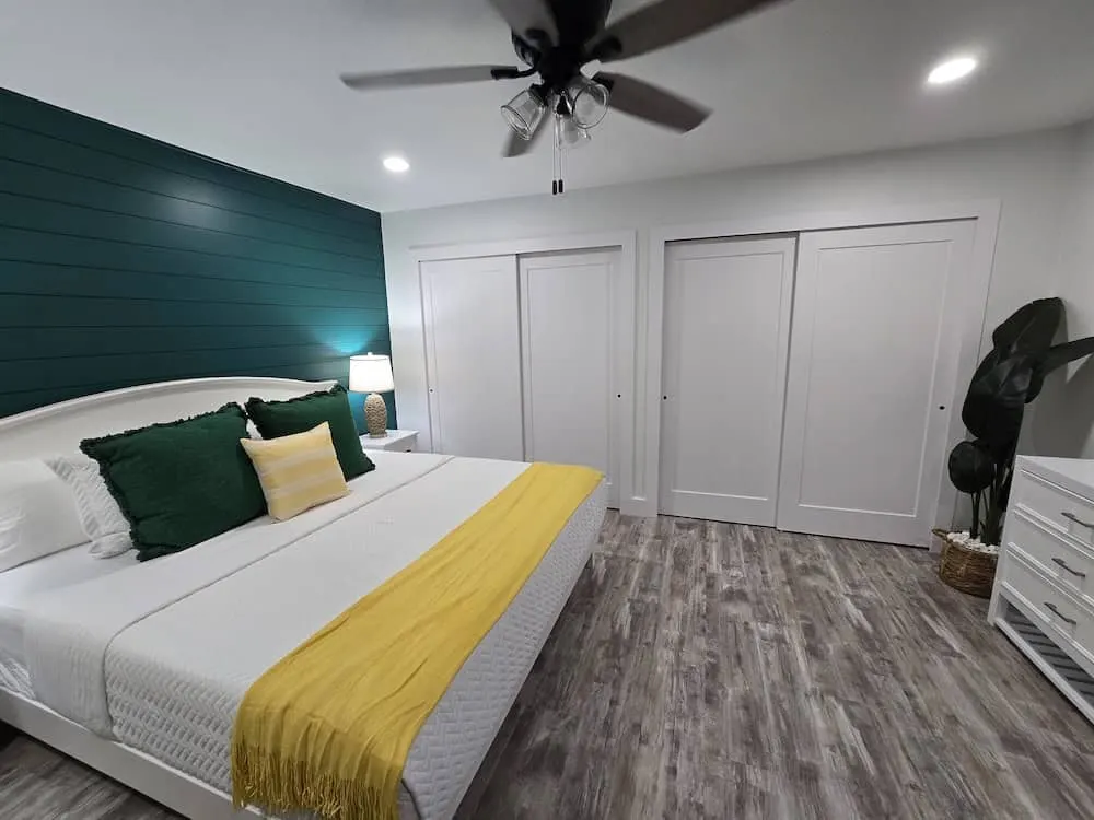 Bedroom with a deep teal shiplap accent wall and white closet doors